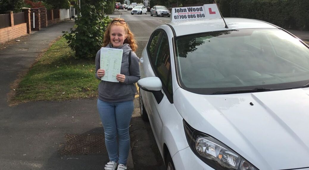 A learner driver celebrates passing her driving test with John Wood School Of Motoring in Southport
