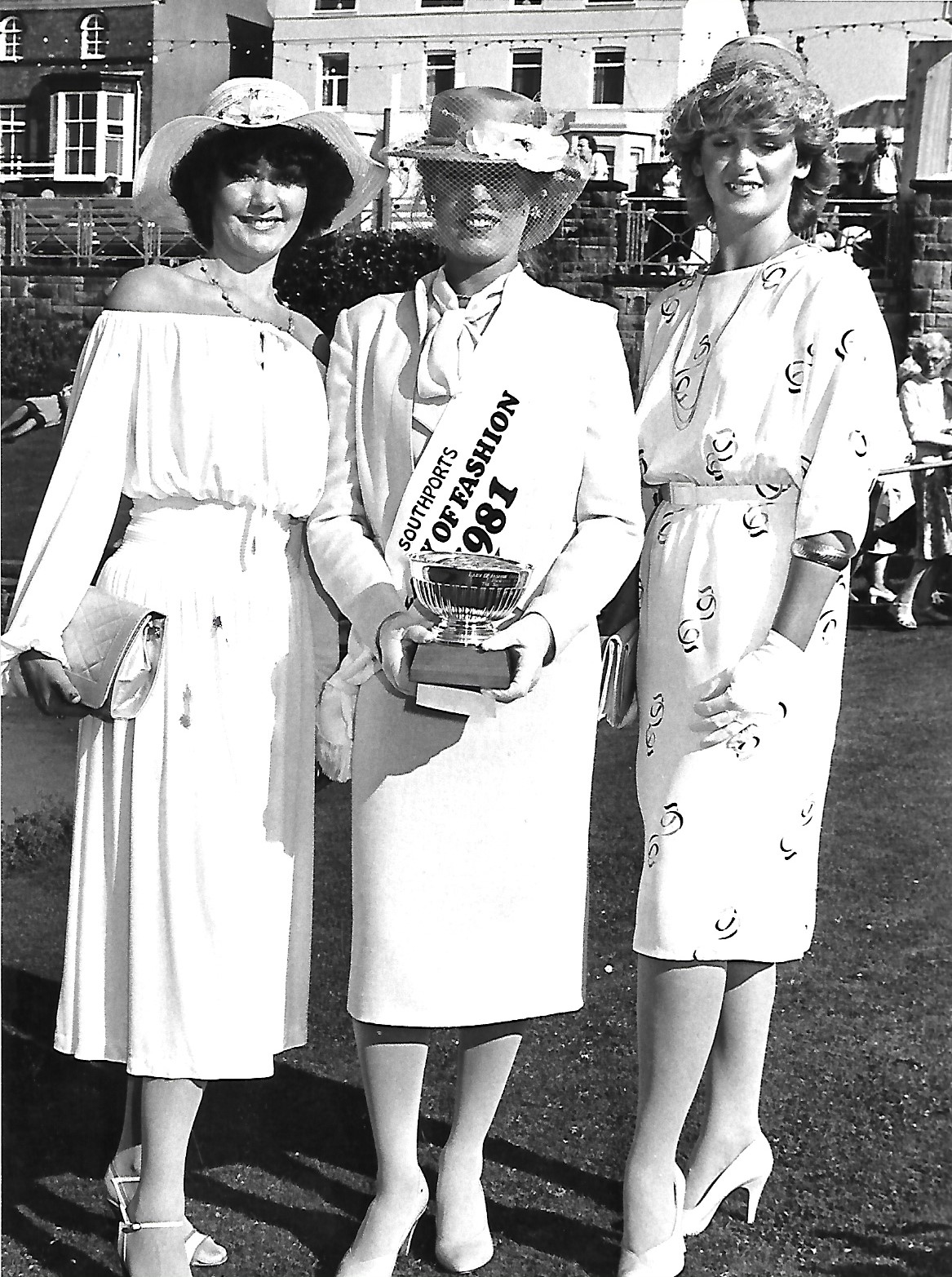 Three very elegant ladies show off their fine dresses and hats - and a handsome looking trophy - at the Southport Lady of Fashion 1981 event in the Floral Hall Gardens