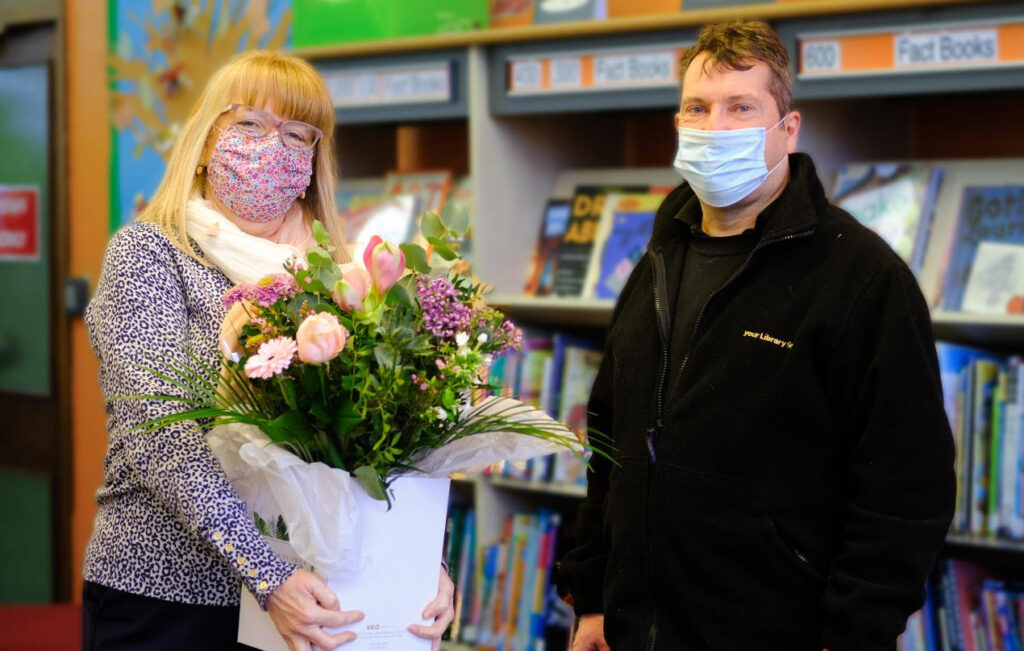Lesley Davies is presented with congratulatory flowers by colleague and friend Andrew Farthing
