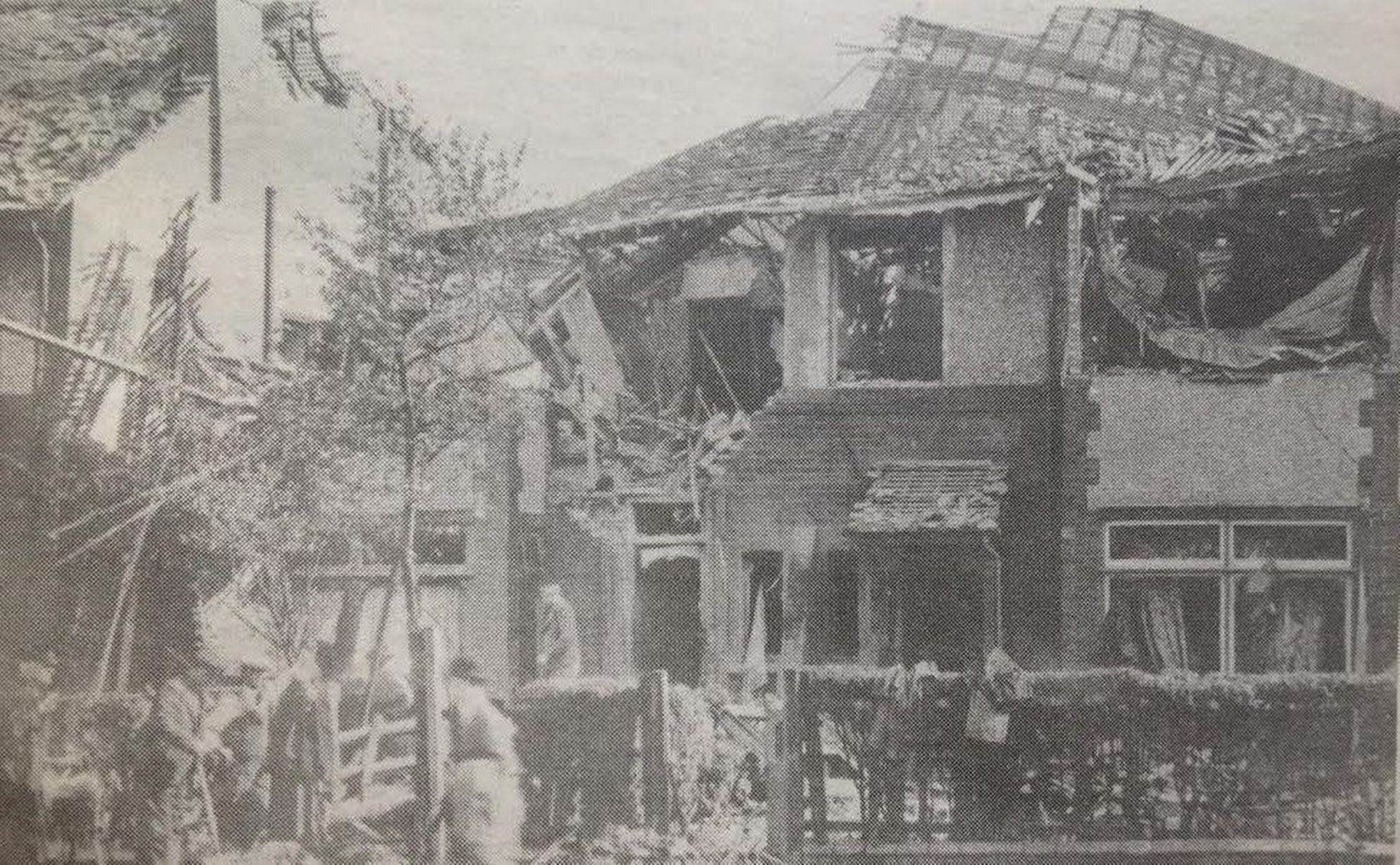 People clear up after bombs from German aircraft destroyed 38 and 40 Manor Avenue in Crosby in the autumn raids of 1940. Life still went on - a passing gent in a bowler hat, rolled umbrella and mackintosh over his arm makes his way to the office