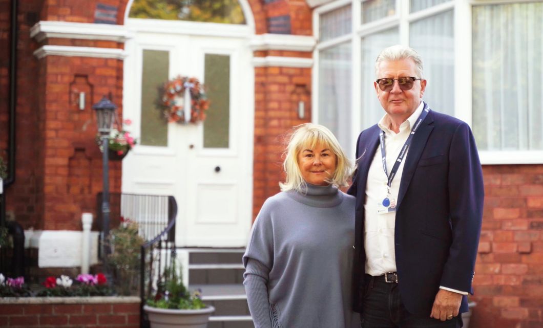 Mark and Wendi Gilbert, stood in front of Dovehaven Residential Home (The Rest Home) in Southport where