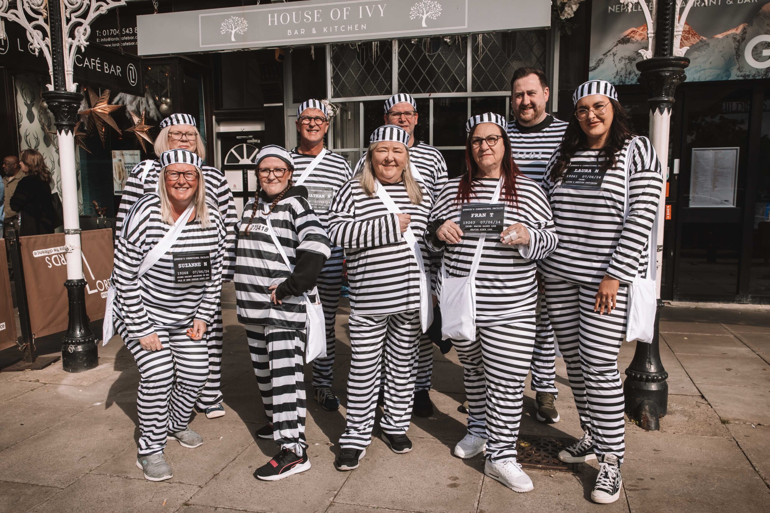 Twelve people have completed a bold escape from the cells at Southport Police Station in the annual Jail and Bail fundraiser for Queenscourt Hospice. Inmates outside the House Of Ivy on Lord Street in Southport 