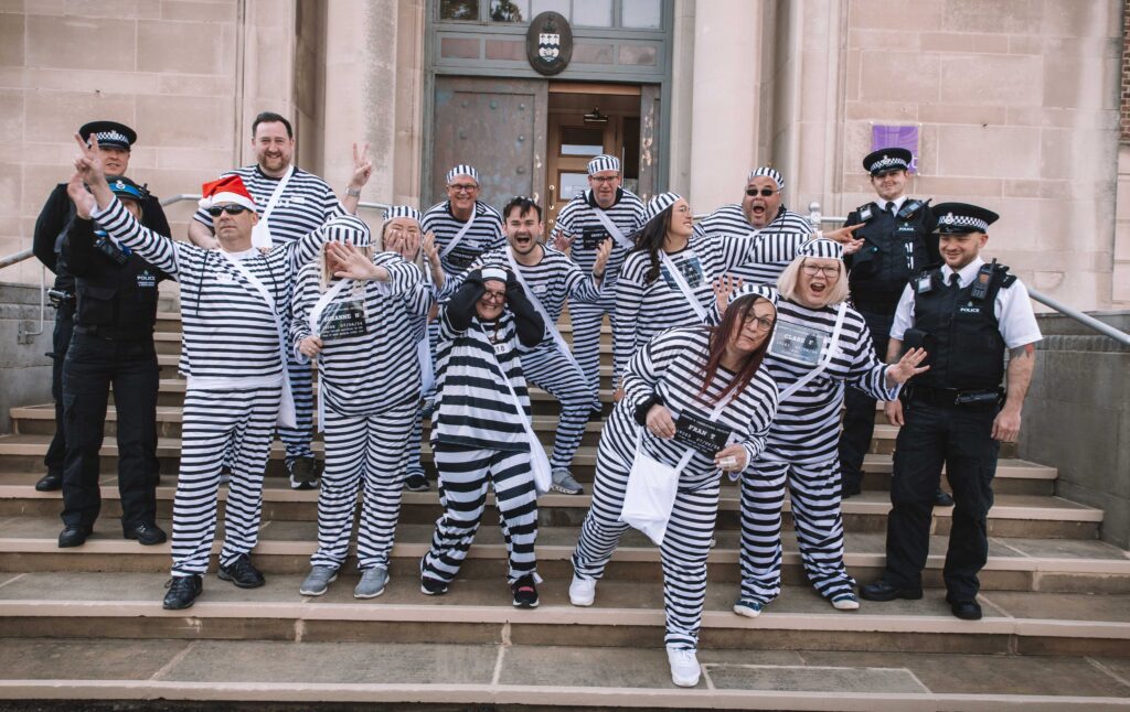 Twelve people have completed a bold escape from the cells at Southport Police Station in the annual Jail and Bail fundraiser for Queenscourt Hospice. Inmates outside the former Southport Magistrates Court (now Access Point) with Sefton Police officers