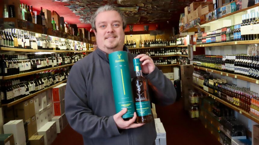 Portland Wine Cellars in Southport. Owner Phil Barber with a bottle of 16 year old Glenfiddich. Photo by Andrew Brown Stand Up For Southport