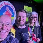 Southport New Comedian Of The Year 2025 Winner Rich McCulloch with Isabelle Kent from Dragon Soop and Festival Director Bren Riley